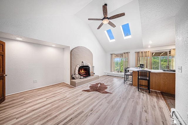 2930 Spielman Rd, Adrian, MI 49221 - living area featuring a baseboard heating unit, a skylight, a ceiling fan, high vaulted ceiling, and wood finished floors