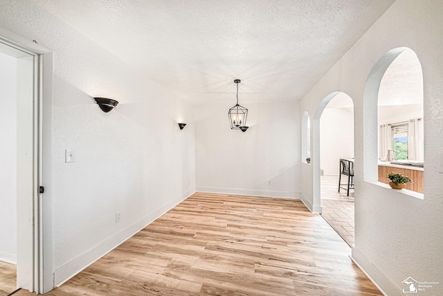 2930 Spielman Rd, Adrian, MI 49221 - hallway featuring arched walkways, light wood-style floors, baseboards, and a textured ceiling