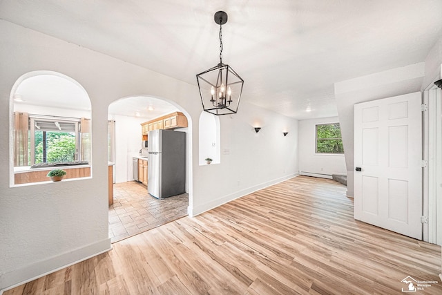 2930 Spielman Rd, Adrian, MI 49221 - unfurnished dining area featuring arched walkways, baseboards, a baseboard radiator, a chandelier, and light wood-style flooring
