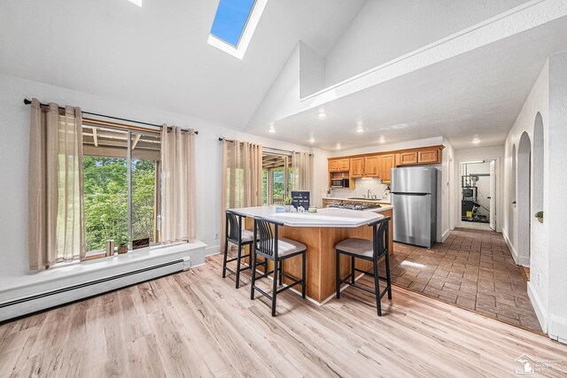 2930 Spielman Rd, Adrian, MI 49221 - kitchen featuring freestanding refrigerator, a baseboard heating unit, black microwave, a breakfast bar, and light countertops