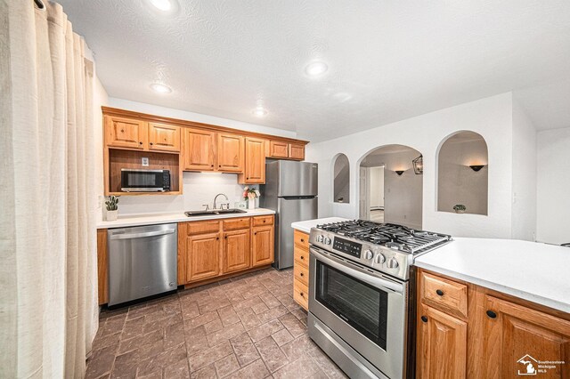 2930 Spielman Rd, Adrian, MI 49221 - kitchen featuring appliances with stainless steel finishes, a sink, light countertops, recessed lighting, and arched walkways