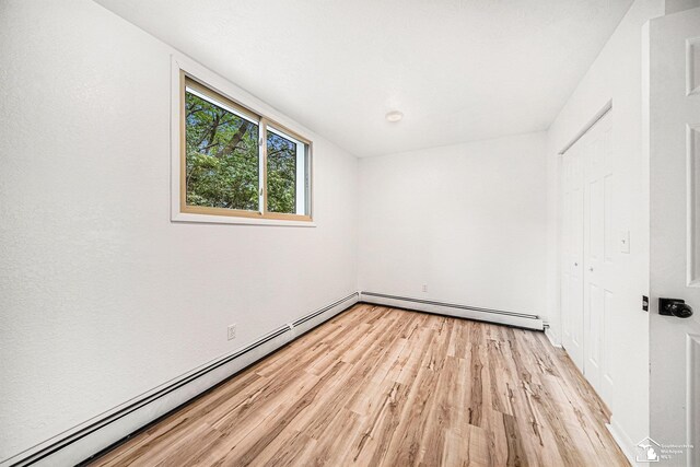 2930 Spielman Rd, Adrian, MI 49221 - unfurnished bedroom with light wood-type flooring, a baseboard radiator, and a closet