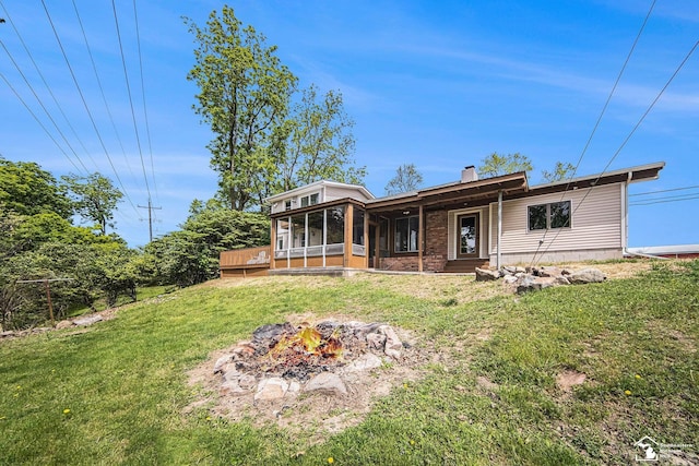 2930 Spielman Rd, Adrian, MI 49221 - rear view of house with a sunroom, a yard, an outdoor fire pit, and a chimney