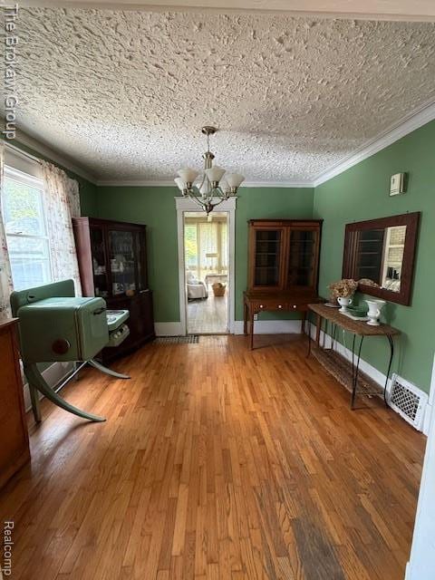 619 W Barnes Ave, Lansing, MI 48910 - dining space with a chandelier, plenty of natural light, wood finished floors, crown molding, and baseboards