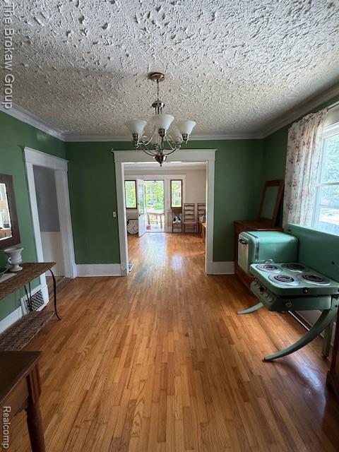 619 W Barnes Ave, Lansing, MI 48910 - dining space featuring a chandelier, ornamental molding, light wood finished floors, baseboards, and a textured ceiling
