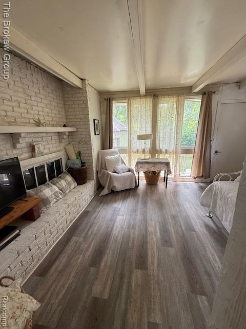 619 W Barnes Ave, Lansing, MI 48910 - living area with beam ceiling, wood finished floors, plenty of natural light, and brick wall