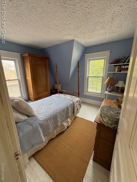 619 W Barnes Ave, Lansing, MI 48910 - bedroom with a textured ceiling and light wood-style floors