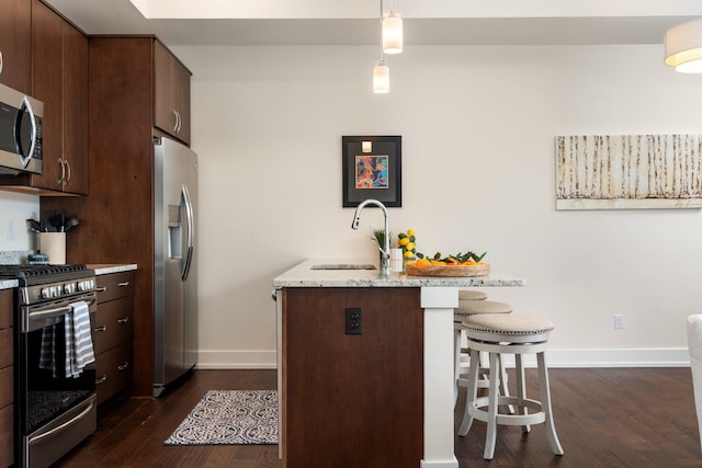 410 N First St Unit 207, Ann Arbor, MI 48103 - kitchen featuring stainless steel appliances, a sink, a breakfast bar, dark wood finished floors, and baseboards