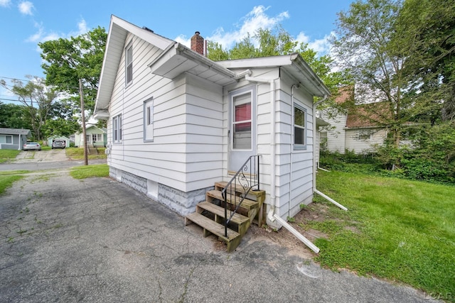 174 W Mansion St, Jackson, MI 49203 - view of side of property featuring entry steps, a chimney, and a lawn