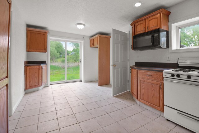 238 Long Ave, Michigan Center, MI 49254 - kitchen with white gas range, black microwave, dark countertops, brown cabinets, and light tile patterned floors