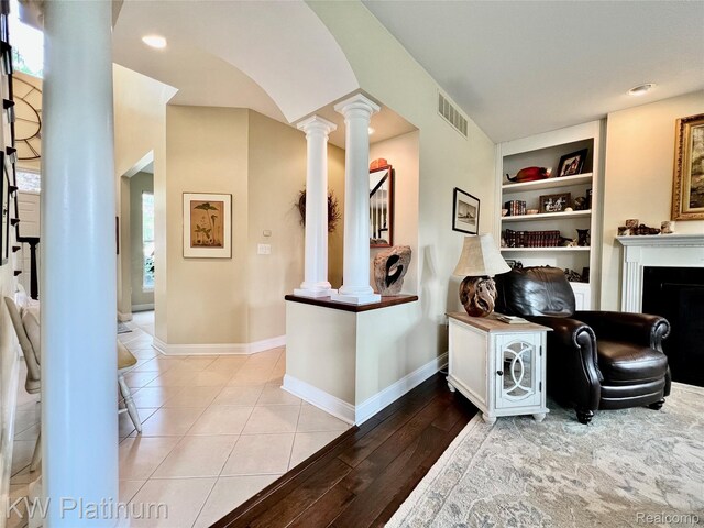 3105 E Woodland Dr, Port Huron, MI 48060 - living area featuring decorative columns, built in shelves, arched walkways, a fireplace, and light wood finished floors