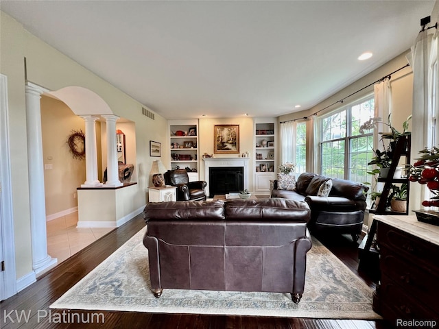 3105 E Woodland Dr, Port Huron, MI 48060 - living area featuring decorative columns, a glass covered fireplace, arched walkways, built in features, and wood finished floors