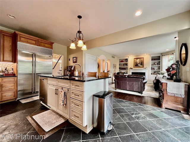3105 E Woodland Dr, Port Huron, MI 48060 - kitchen with appliances with stainless steel finishes, dark countertops, a kitchen island with sink, recessed lighting, and decorative light fixtures