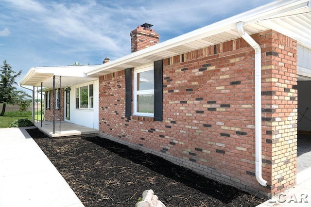 1443 N Posey Lake Rd, Hudson, MI 49247 - view of home's exterior featuring a chimney, covered porch, and brick siding