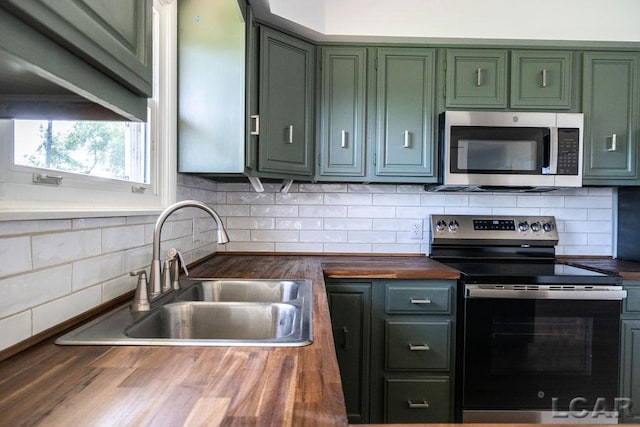 1443 N Posey Lake Rd, Hudson, MI 49247 - kitchen featuring appliances with stainless steel finishes, wood counters, green cabinets, a sink, and backsplash