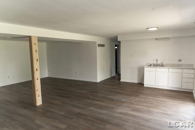 1443 N Posey Lake Rd, Hudson, MI 49247 - unfurnished living room with dark wood-style floors, bar with sink, baseboards, and a textured ceiling