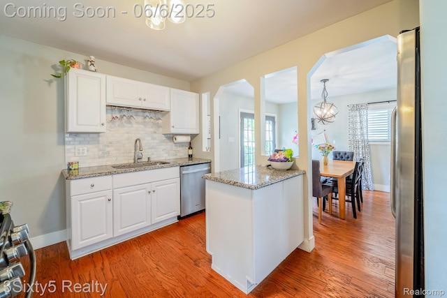 3831 Durham Rd, Royal Oak, MI 48073 - kitchen with dishwasher, a sink, arched walkways, a chandelier, and white cabinetry