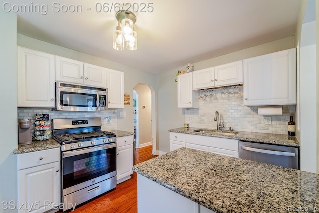 3831 Durham Rd, Royal Oak, MI 48073 - kitchen featuring appliances with stainless steel finishes, a sink, arched walkways, tasteful backsplash, and wood finished floors