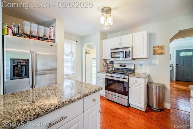 3831 Durham Rd, Royal Oak, MI 48073 - kitchen featuring stainless steel appliances, arched walkways, white cabinetry, and light wood-type flooring