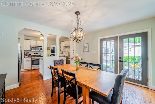 3831 Durham Rd, Royal Oak, MI 48073 - dining area with light wood finished floors, arched walkways, french doors, a chandelier, and baseboards