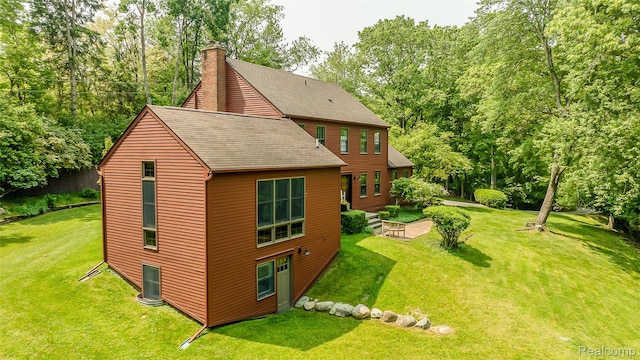 2694 Wayside Dr, Ann Arbor, MI 48103 - view of side of home featuring roof with shingles, a chimney, a yard, and view of wooded area