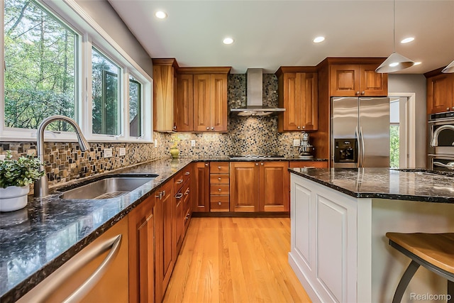 2694 Wayside Dr, Ann Arbor, MI 48103 - kitchen with appliances with stainless steel finishes, wall chimney exhaust hood, brown cabinets, light wood-type flooring, and dark stone counters