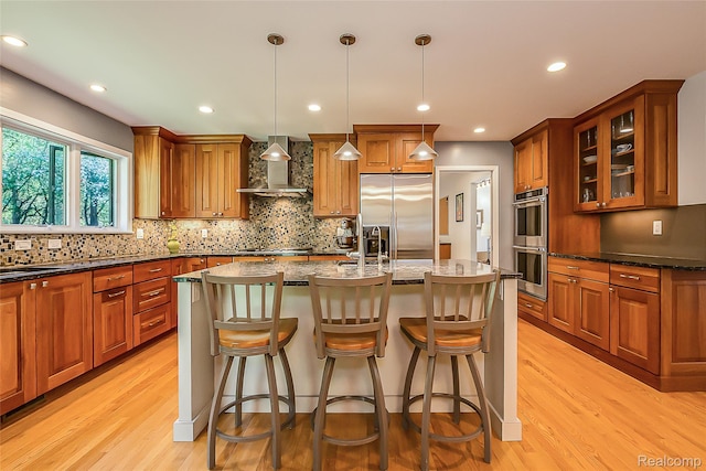 2694 Wayside Dr, Ann Arbor, MI 48103 - kitchen with appliances with stainless steel finishes, wall chimney range hood, light wood-style floors, brown cabinetry, and recessed lighting