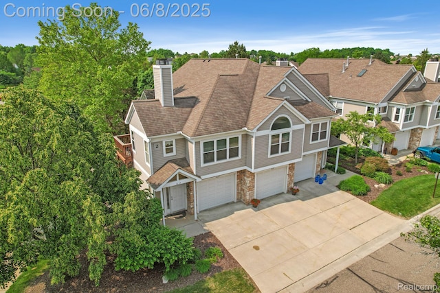 1637 Coburn Dr, Ann Arbor, MI 48108 - view of front facade featuring stone siding, driveway, a garage, a chimney, and roof with shingles