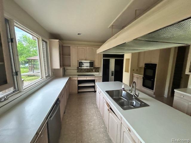 6880 Burtonwood Dr, West Bloomfield, MI 48322 - kitchen featuring a sink, stainless steel appliances, light countertops, wall chimney range hood, and white cabinetry