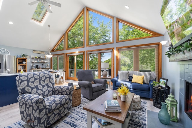 11815 Waldron Rd, Jerome, MI 49249 - living room featuring a ceiling fan, high vaulted ceiling, a lit fireplace, a skylight, and recessed lighting