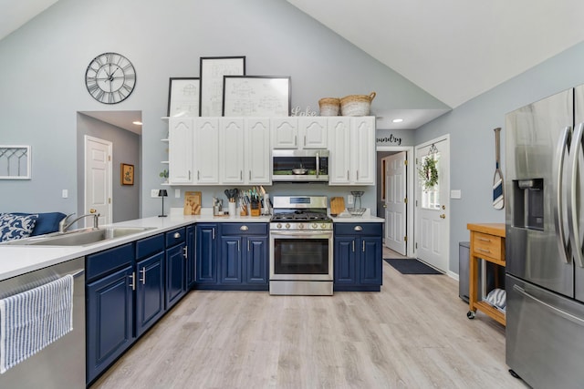 11815 Waldron Rd, Jerome, MI 49249 - kitchen featuring appliances with stainless steel finishes, high vaulted ceiling, blue cabinets, a sink, and white cabinets