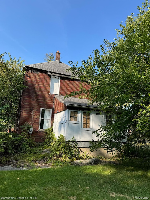 2986 Cadillac Blvd, Detroit, MI 48214 - rear view of house with a chimney, brick siding, and a lawn