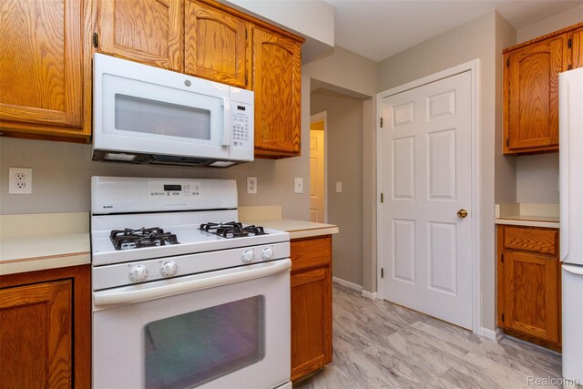 53395 Andrew Cir, New Baltimore, MI 48047 - kitchen featuring white appliances, light countertops, brown cabinetry, and baseboards