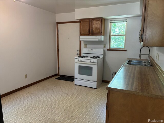 1096 Bayfield St, Lake Orion, MI 48362 - kitchen featuring white gas stove, under cabinet range hood, and brown cabinetry