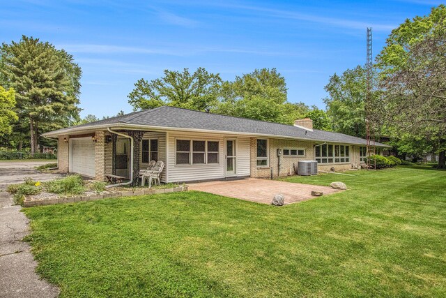 1205 Sassafras Ln, Niles, MI 49120 - back of property featuring an attached garage, central air condition unit, a yard, asphalt driveway, and a chimney