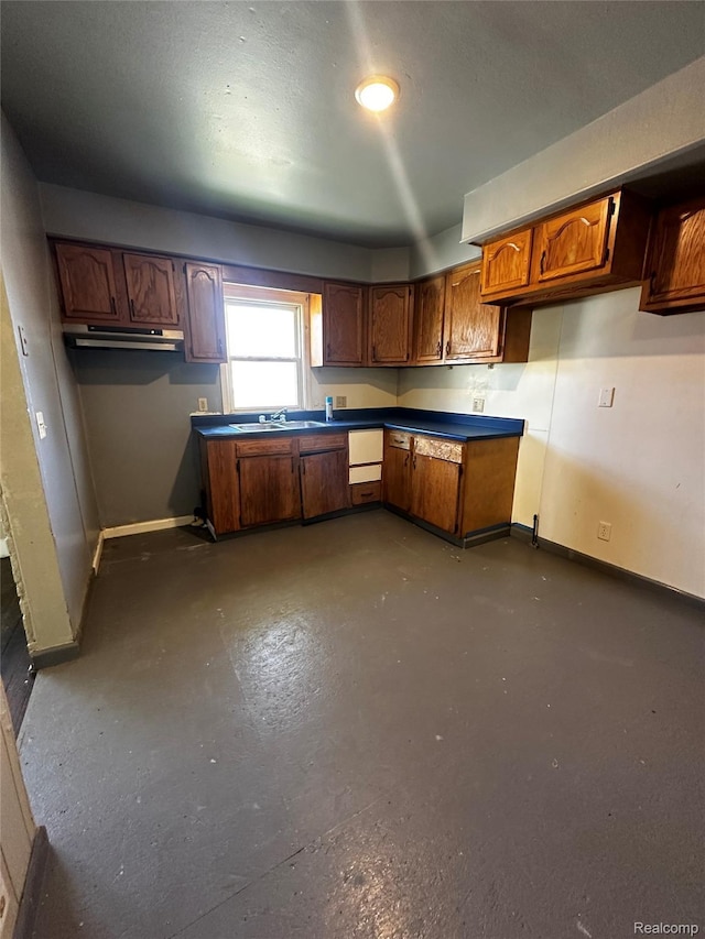 2500 Salt St, Saginaw, MI 48602 - kitchen with baseboards, under cabinet range hood, brown cabinetry, and a sink