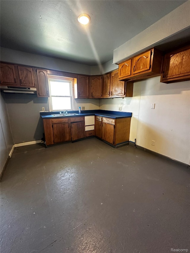 2500 Salt St, Saginaw, MI 48602 - kitchen with baseboards, under cabinet range hood, concrete flooring, and brown cabinetry