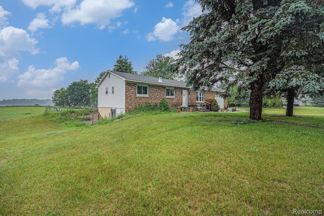 7184 Grand River Rd, Bancroft, MI 48414 - rear view of house with brick siding, a lawn, and a garage