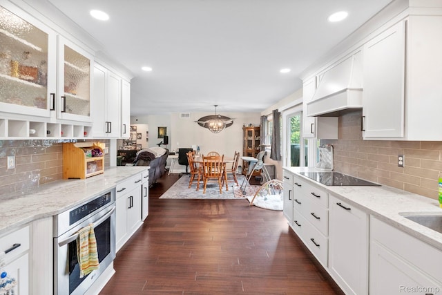 116 Surrey Rd, Saint Louis, MI 48880 - kitchen featuring oven, black electric cooktop, premium range hood, white cabinetry, and glass insert cabinets