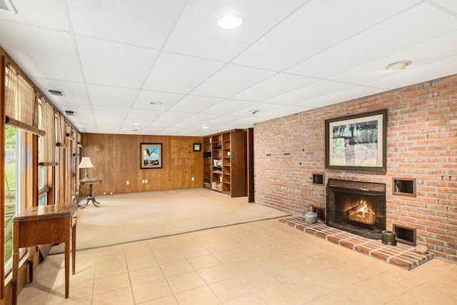 22649 N Dixboro Rd, South Lyon, MI 48178 - unfurnished living room with carpet, a drop ceiling, wood walls, a fireplace, and tile patterned floors