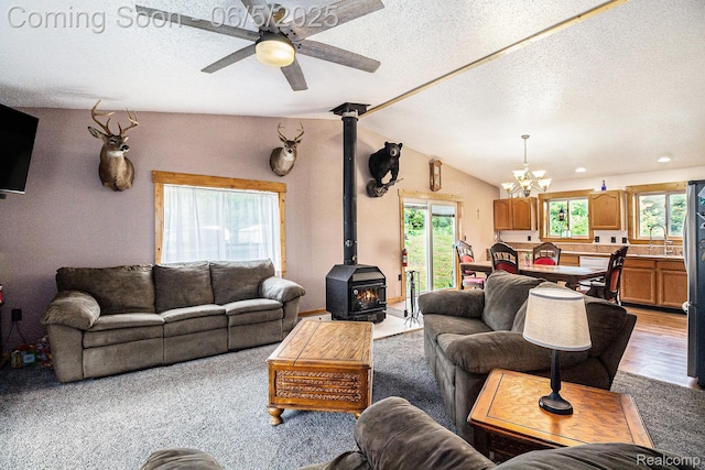 3275 Levalley Rd, Columbiaville, MI 48421 - living area with a wood stove, a chandelier, ceiling fan, lofted ceiling, and a textured ceiling