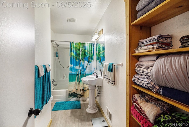 3275 Levalley Rd, Columbiaville, MI 48421 - full bathroom with wood finished floors, shower / bathtub combination with curtain, baseboards, and a textured wall