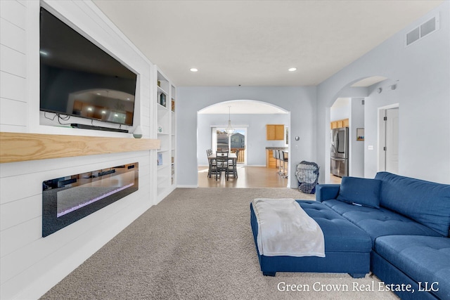 4052 Quest Ct SW, Wyoming, MI 49418 - living room featuring arched walkways, carpet flooring, recessed lighting, built in features, and a glass covered fireplace