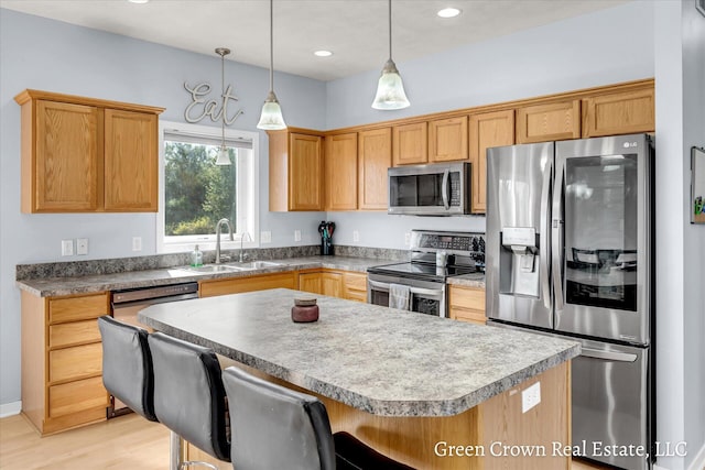 4052 Quest Ct SW, Wyoming, MI 49418 - kitchen featuring appliances with stainless steel finishes, a sink, a kitchen bar, a kitchen island, and decorative light fixtures