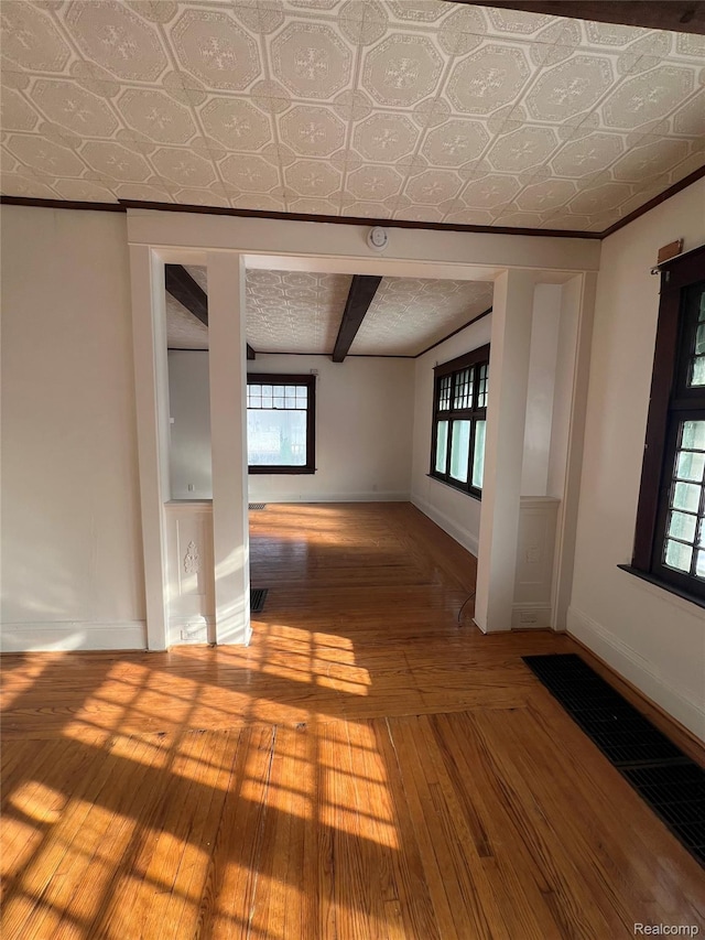 3137 S Washington Ave, Saginaw, MI 48601 - empty room featuring baseboards, wood-type flooring, healthy amount of natural light, and an ornate ceiling
