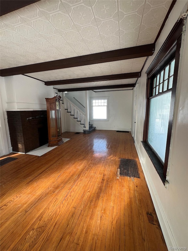 3137 S Washington Ave, Saginaw, MI 48601 - unfurnished living room featuring beamed ceiling, wood finished floors, stairs, and baseboards