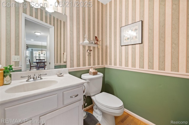 2336 Swans Cv Unit 7, Fenton, MI 48430 - half bathroom featuring wood finished floors, vanity, and wallpapered walls