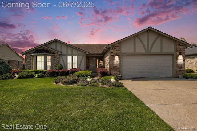 16256 Karen Dr, Clinton Township, MI 48038 - tudor home with concrete driveway, an attached garage, a lawn, and brick siding