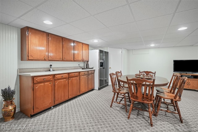 2391 Atwell Rd, Attica, MI 48412 - kitchen featuring refrigerator with ice dispenser, light carpet, light countertops, brown cabinetry, and a paneled ceiling