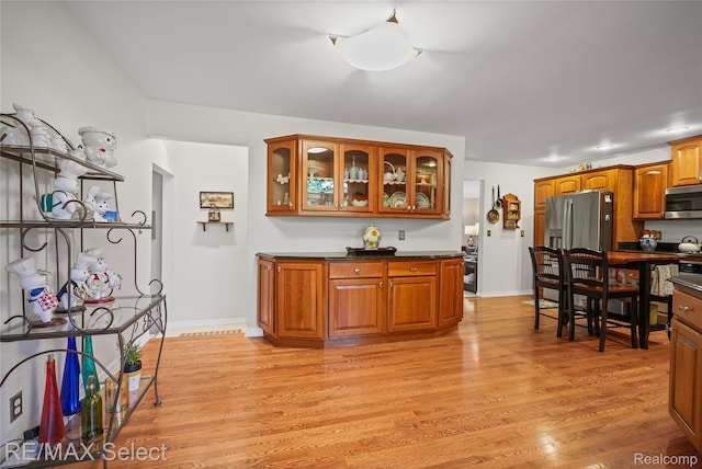 2391 Atwell Rd, Attica, MI 48412 - kitchen featuring stainless steel appliances, dark countertops, light wood-style flooring, and glass insert cabinets